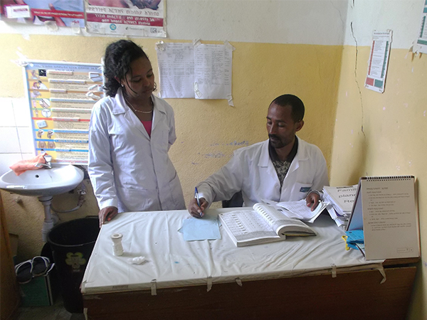 health workers reviewing patient intake ledger