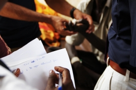 © Photo by Samuel Boland, courtesy of Photoshare, 2011. A student in Juba, South Sudan takes notes as a physician explains how to assess a patient.